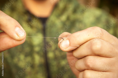 the fisherman attaches the hook to the line, close-up