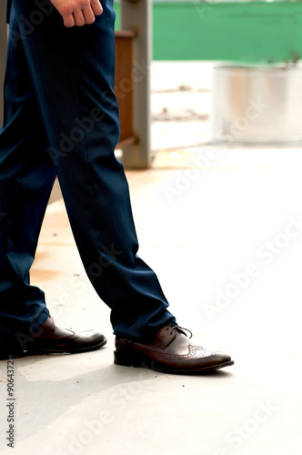 Feet man in brown shoes outdoors.