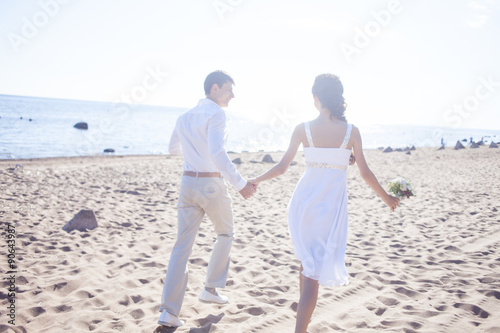 Just married happy couple running on a sandy beach