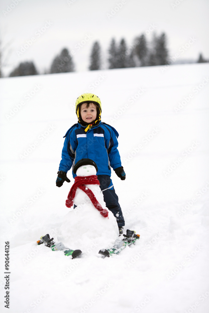 Happy little boy playing in the snow while snowing, helmet Happy little boy playing in the snow while snowing, helmet