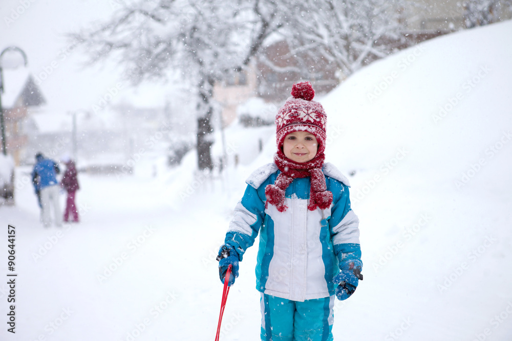 Cute little boy in blue winter suit, playing outdoor in the snow