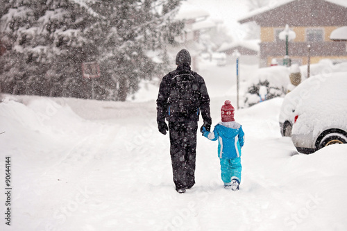 Young father and son, walking hand in hand down the street