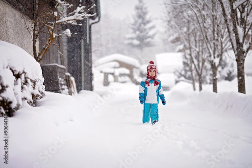 little boy in a snowsuit walking through a snowy path with deep © Tomsickova
