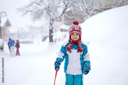 Cute little boy in blue winter suit, playing outdoor in the snow