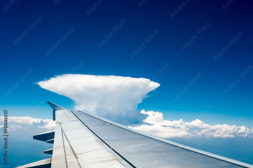 Wing of  airplane  flying above the cloud like nuclear mushroom