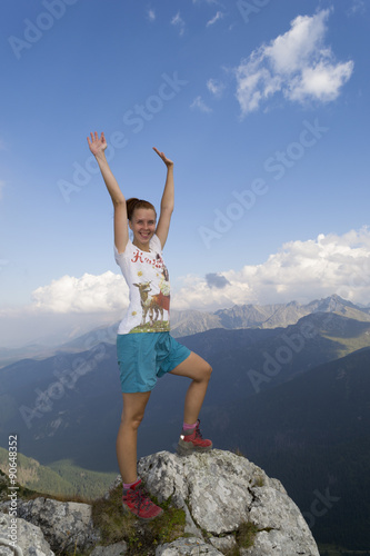 Happy woman reached summit with raised hands in the air
