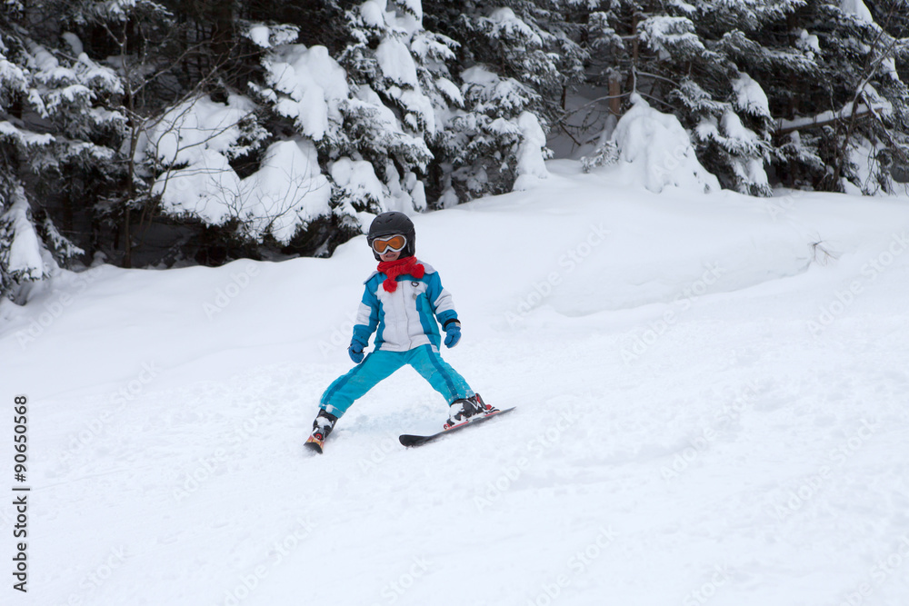 Adorable little boy with blue jacket and a helmet, skiing