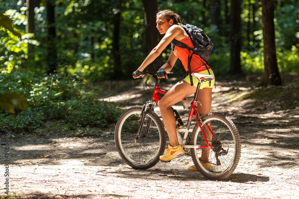 Gracefully biking through the forest, a skilled female athlete enjoys the mountain bike ride.