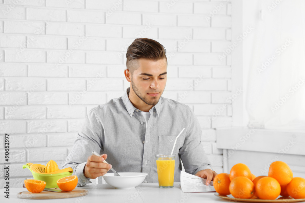 Young man having breakfast with oranges Young man having breakfast with oranges