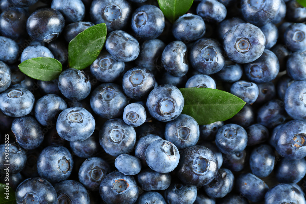 Obraz premium Tasty ripe blueberries with green leaves close up