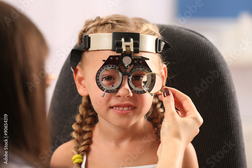Young girl undergoing eye test with Spectacles on blurred background