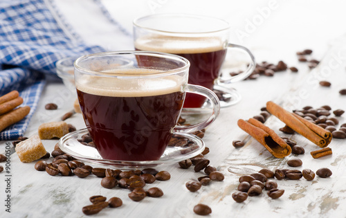 Two Glass Coffee cups and beans on a wooden background.