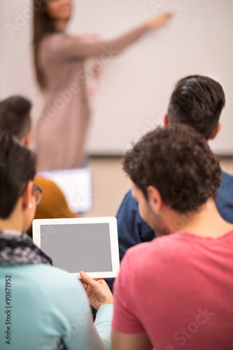 Two students watching tablet while professor giving lecture