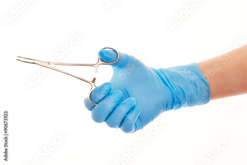 Close up of female doctor's hand in blue sterilized surgical glove with forceps against white background
