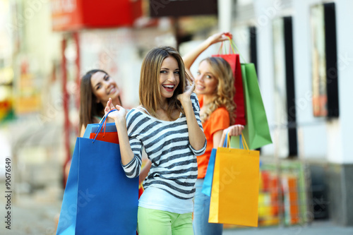 Beautiful young women with shopping bags on city street