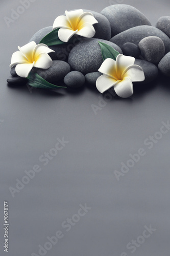 Spa stones with flowers on gray background