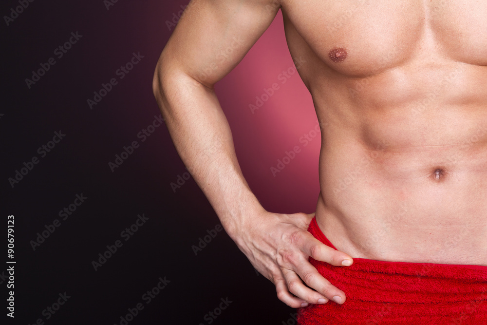 Fit man in red towel against dark background