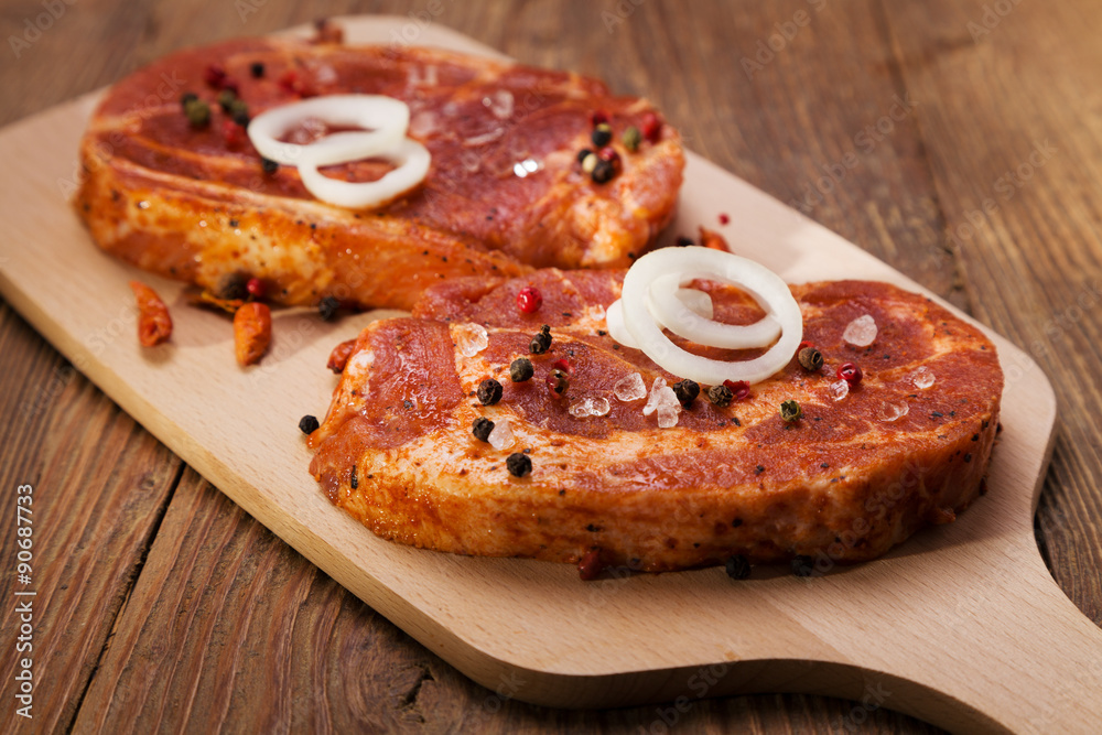 Marinated, raw pork ready for roasting on a wooden table. Marinated, raw pork ready for roasting on a wooden table.