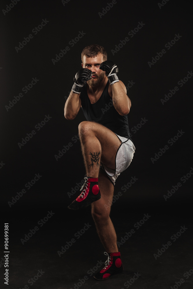 Athletic bearded boxer with gloves on a dark background