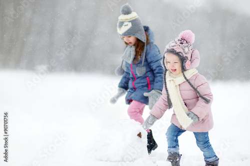 Two funny adorable little sisters in winter park