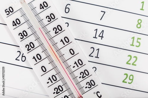 Classic thermometer sitting on a calendar sheet