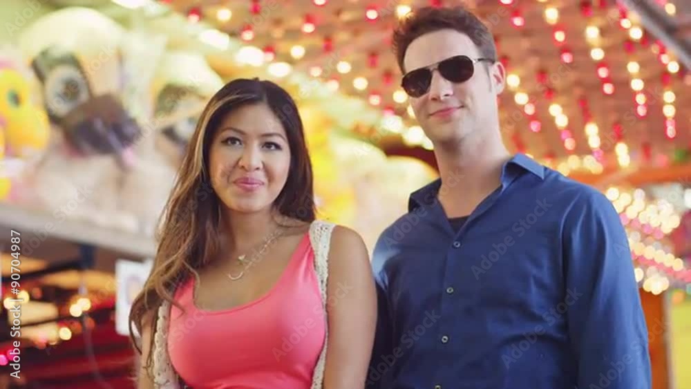 Close up of a couple feeding each other cotton candy at a fair
