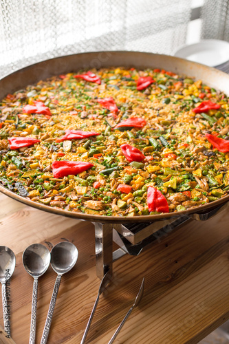 A large pot of paella on a wooden table bright colorful homemade authentic traditional feast