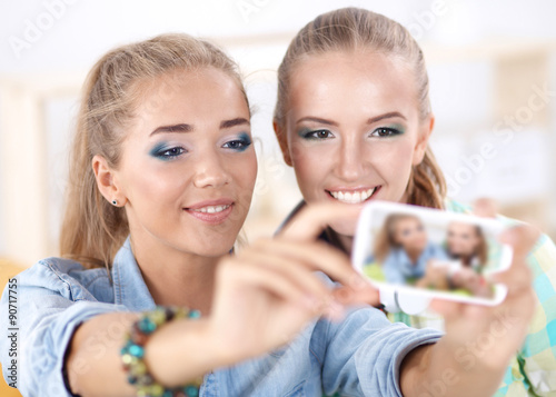 Two girls taking pictures on the phone at home