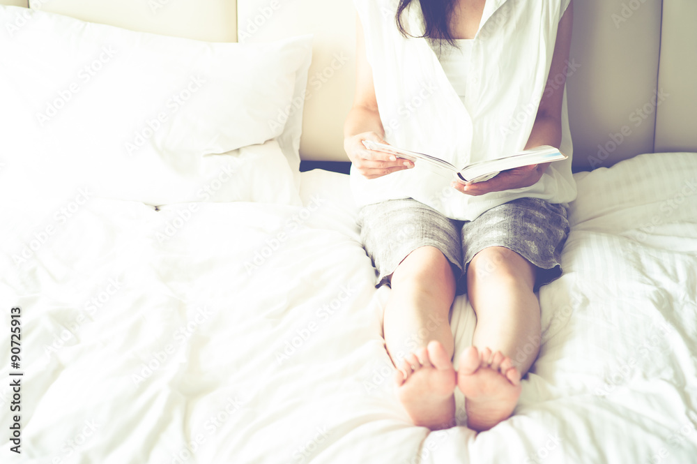 ベッドの上で本を読む女性 ベッドの上で本を読む女性
