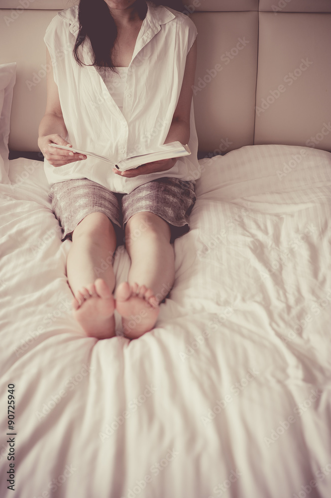ベッドの上で本を読む女性 ベッドの上で本を読む女性