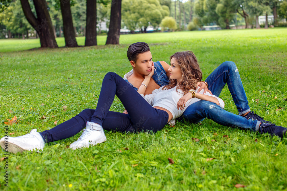 Casual male and female lying on grass field in a park.