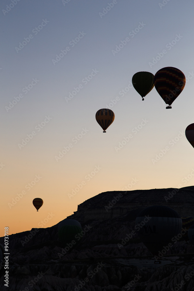 Obraz premium Ballons in the eraly morning over rocks in cappadocia