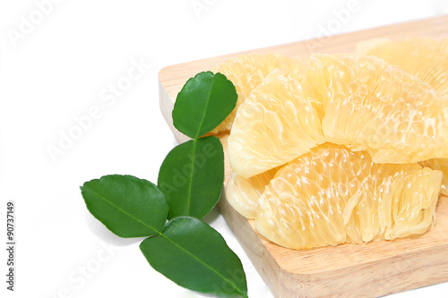 pomelo ripe laying on a wooden cutting board white background