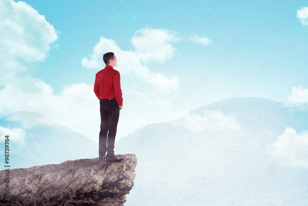 Asian business man standing on the top of the mountain