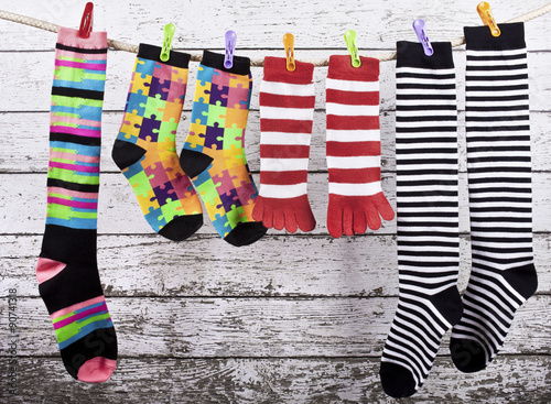 Funny colorful socks are drying on the clothesline on wooden background painted walls