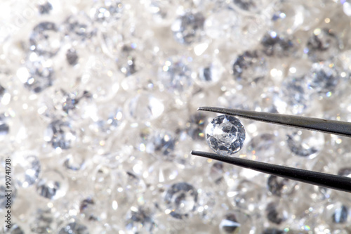 diamond held by tweezers close up. more diamonds out of focus in