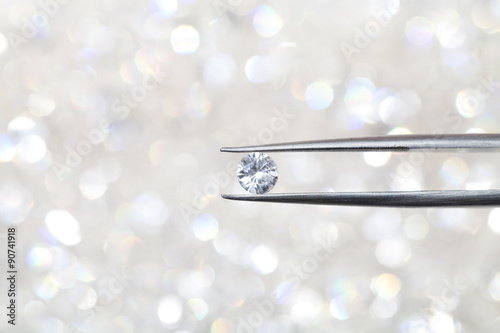 diamond held by tweezers close up. more diamonds out of focus in