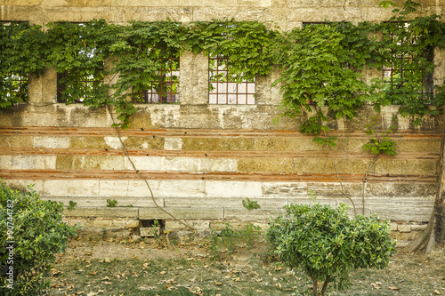 Old wall of a building with four windows and grilles