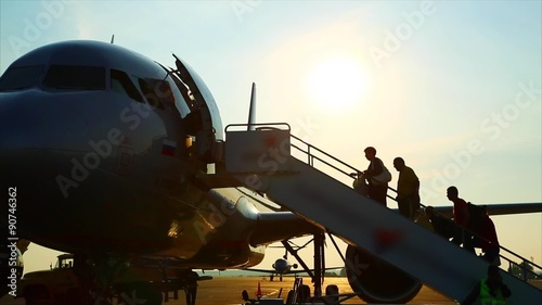 People climb the ladder into the plane, airport