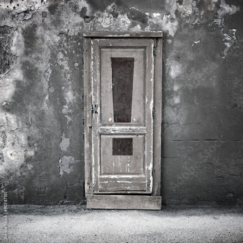 Old door in dark concrete wall with exclamation sign © evannovostro