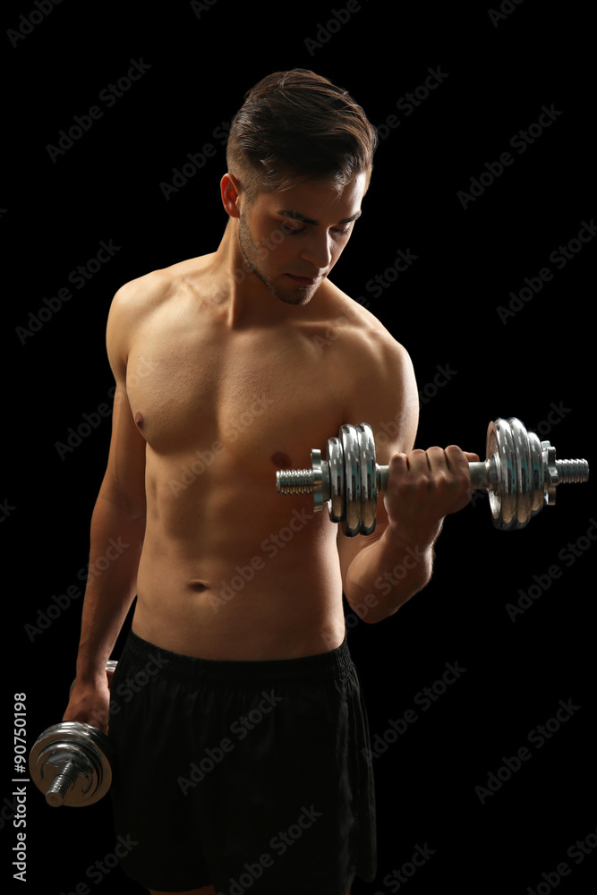 Muscle young man holding dumbbells on dark background