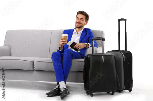 Business man with suitcase sitting on sofa isolated on white