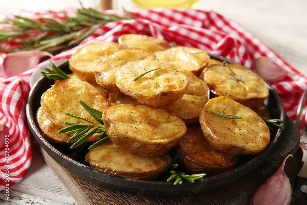 Delicious baked potato with rosemary in frying pan on table close up Delicious baked potato with rosemary in frying pan on table close up