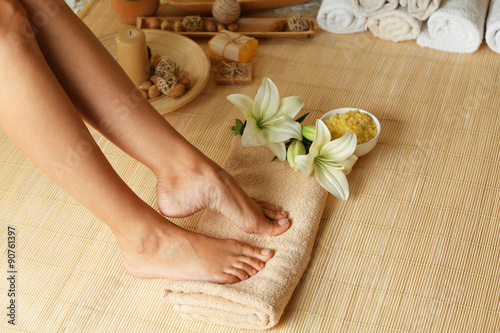 Female feet on soft towel over bamboo mat background
