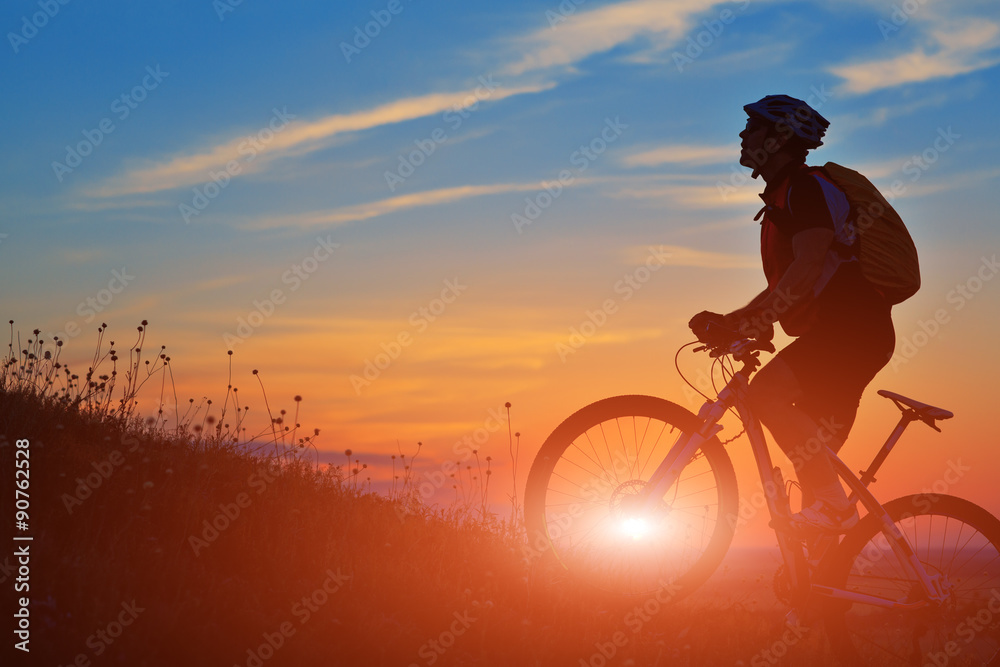 Fototapeta premium Silhouette of a biker and bicycle on sky background.