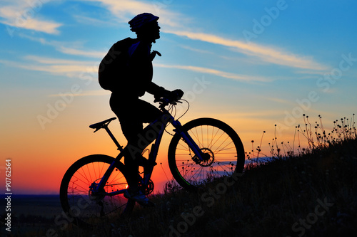 Fototapeta Naklejka Na Ścianę i Meble -  Silhouette of a biker and bicycle on sky background.