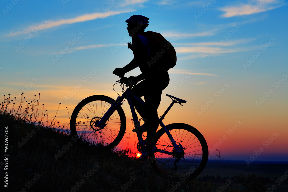 Obraz premium Silhouette of a biker and bicycle on sky background.