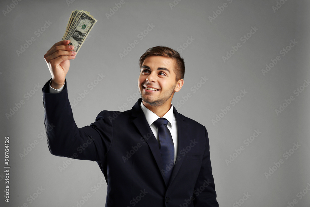 Elegant man in suit holding money on gray background Elegant man in suit holding money on gray background