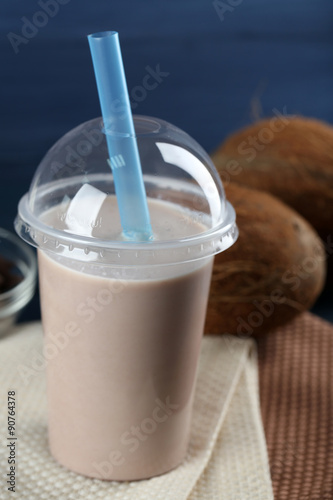 Plastic cup of milkshake on color wooden background