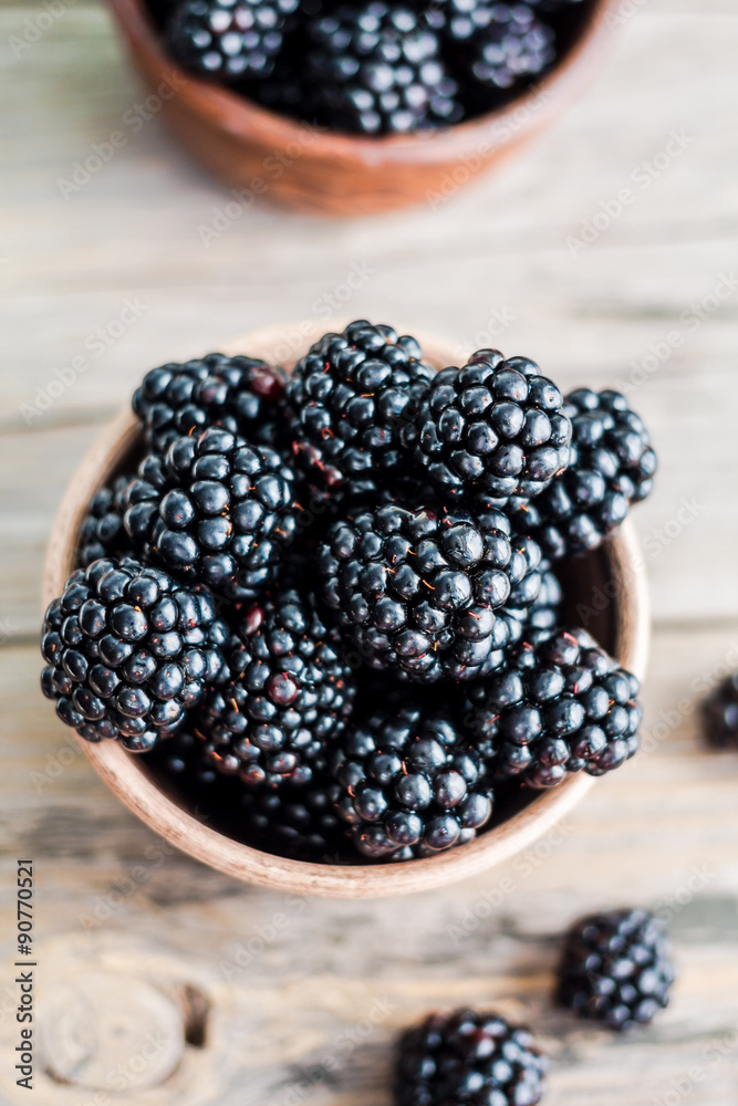 Fresh sweet blackberry in clay pots on a wooden table, closeup Fresh sweet blackberry in clay pots on a wooden table, closeup